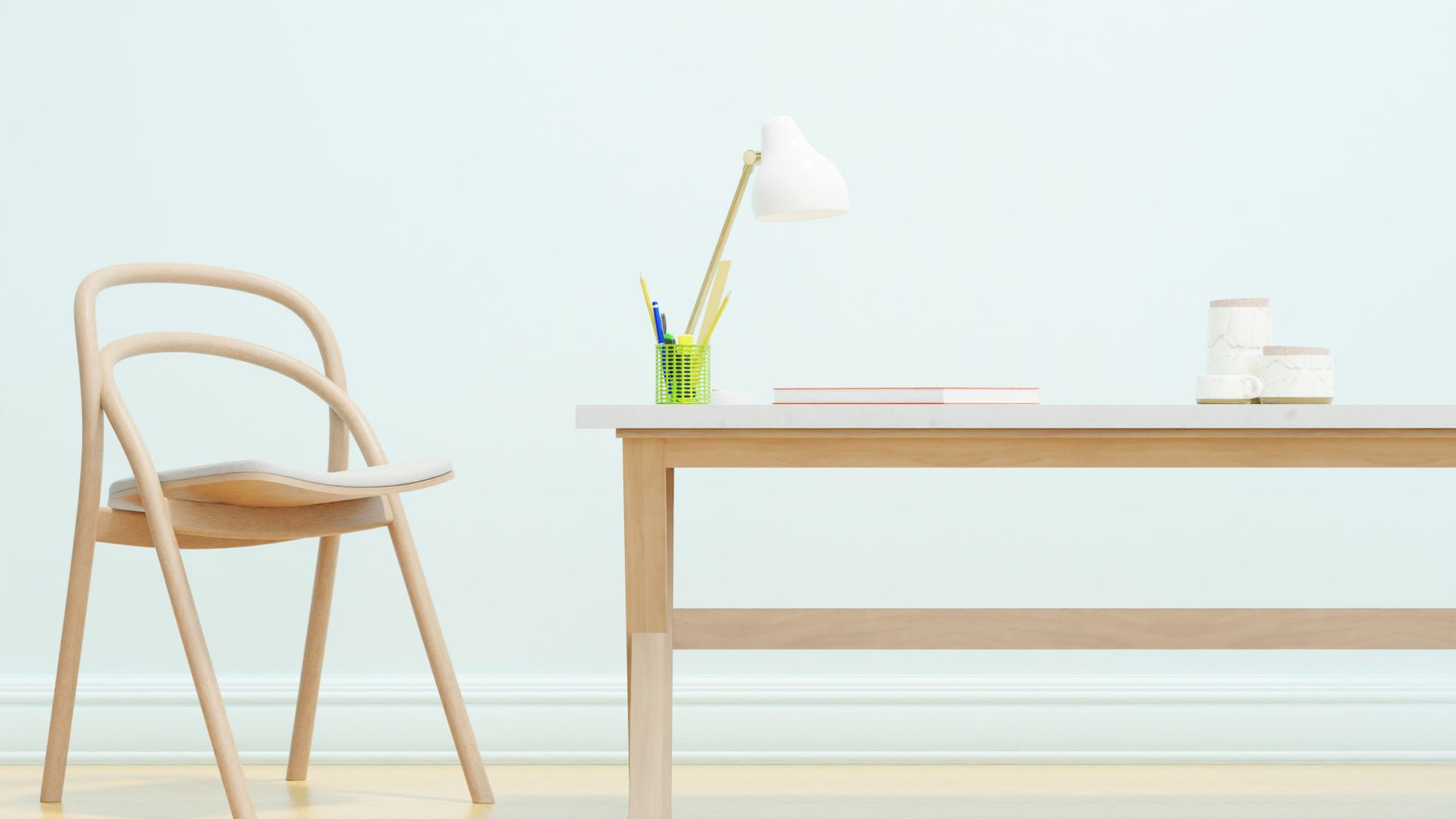 Et enkelt skrivebord med en stol og en lampe mod en lys væg