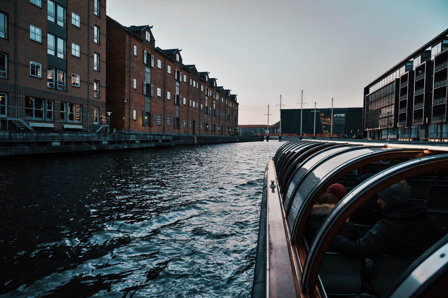 En kanal mellem murstensbygninger med en turbåd i forgrunden